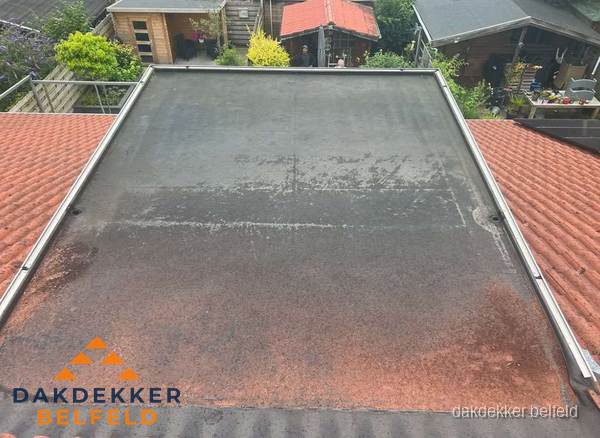 Verouderd plat dak met slijtage tussen schuine daken in Belfeld Verouderd plat dak met slijtage tussen schuine daken in Belfeld
